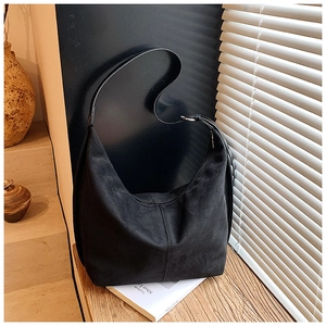 Detail of black suede large shoulder bag showing crescent shape and silver hardware