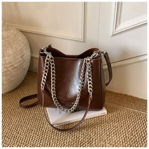 Detailed view of dark brown vintage bucket bag with silver metal chain and oil-wax leather
