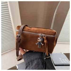 Close-up of brown suede crossbody bag with a silver robot charm and metal zipper