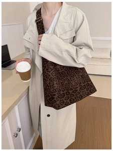 Detail of leopard print tote bag with adjustable wide strap shown on a beige trench coat