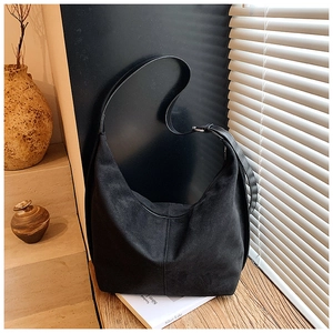 Detail of minimalist black suede hobo bag with adjustable strap and silver metal buckle
