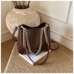 Close-up of a vintage brown bucket bag with thick silver chain and leather strap details