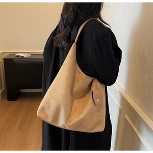 Detailed texture of a camel faux suede hobo bag styled with a professional black coat