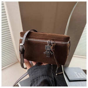 Detail of vintage brown suede crossbody bag featuring a unique metal robot charm accessory