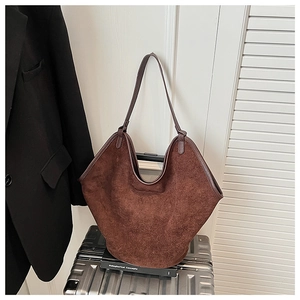Detail of dark brown suede tote bag hanging on silver luggage for travel styling