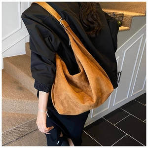 Detail of tan faux suede hobo bag texture and wide strap with silver metal buckle