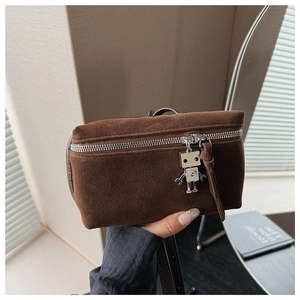 Close-up of brown suede crossbody bag featuring a unique silver metal robot pendant