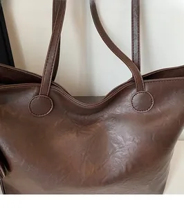 Detail of reinforced circular strap attachment on a brown leather minimalist tote bag