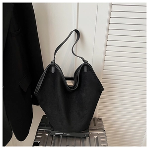 Detail of minimalist black matte suede tote bag with slim straps against a studio background