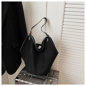 Large black suede tote bag placed on a silver suitcase for business travel context