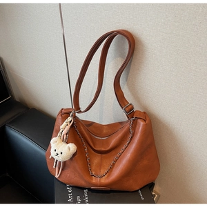 Detail der karamellbraunen PU-Leder Hobo-Tasche mit Silberkette und Plüschbär-Anhänger