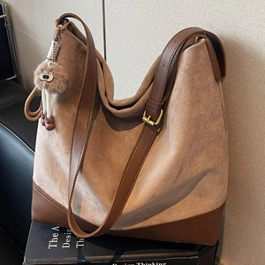 Brown suede hobo bag with leather trim and adjustable strap on books display