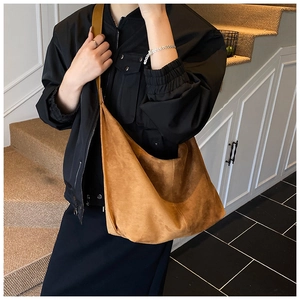Detailed texture of brown faux suede large hobo bag with wide shoulder strap on model