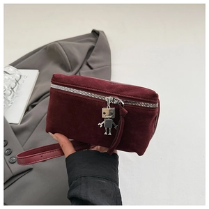 Close-up of burgundy suede crossbody bag featuring a unique silver robot charm detail