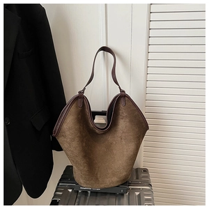 Detailed close-up of brown suede tote bag with leather trim on a metal suitcase