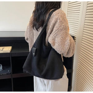 Detailed view of the black suede tote bag with slim leather straps and soft matte texture