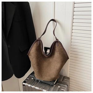 Macro detail of dark brown suede tote bag with leather straps on a vintage suitcase