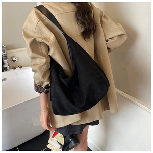 Side view of black suede hobo bag on shoulder showing large capacity and drape