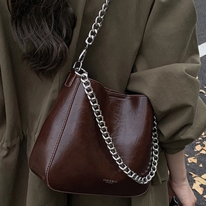 Vintage dark brown wrinkled PU bucket bag with bold silver chain worn over a winter coat