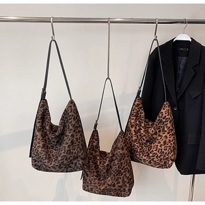 Trois variantes de sacs hobo à imprimé léopard exposées sur un support métallique