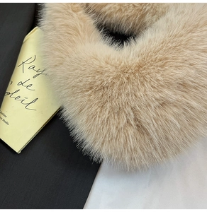 Close-up detail of soft beige faux fox fur material on a stylish plush handbag