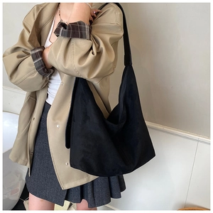 Side view of large black suede tote bag on shoulder showing spacious minimalist design
