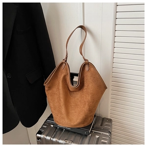 Close-up of brown suede tote bag on metallic suitcase in a sophisticated urban setting