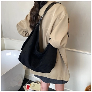 Side view of a large black suede crescent hobo bag worn by a model in a casual setting