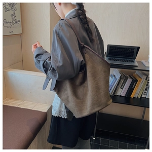 Deep brown suede tote bag shown on shoulder in a modern minimalist office setting