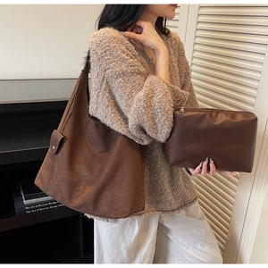 Detail of suede crossbody bag set with smooth leather clutch pouch in warm ambient lighting