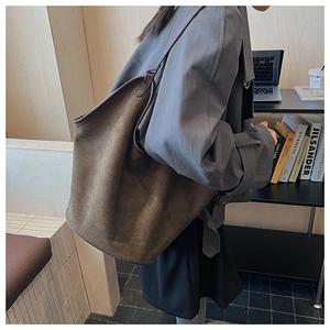 Detail of a large vintage brown faux suede tote bag shown in a professional lifestyle setting