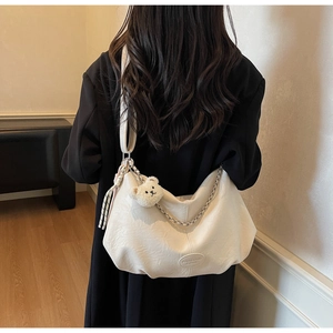 Detailansicht der cremefarbenen Oversize-Shopper mit Bärenanhänger und Silberkette