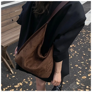 Detail view of large brown faux suede tote bag featuring a soft matte texture and wide shoulder strap
