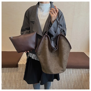 Close-up of olive brown suede tote bag and dark brown leather clutch bag with slim handles