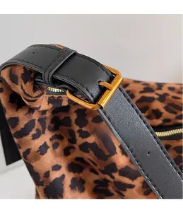 Détail du sac seau léopard avec boucles métalliques dorées et bandoulière en cuir noir