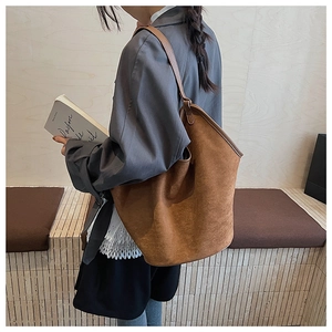 Side view of a large brown suede tote bag on a model showing natural drape and texture