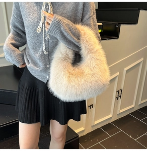 Detailed close-up of a soft cream faux fur tote bag held against a minimalist background