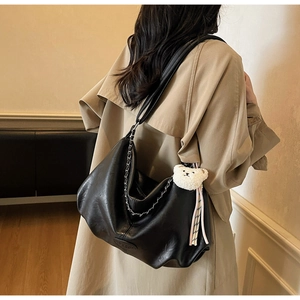 Detail der schwarzen Ledertasche mit Silberkette und süßem Teddybär-Anhänger