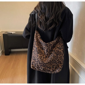 Détail d'un grand sac hobo à imprimé léopard porté par un mannequin dans une pièce minimaliste