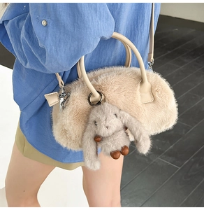 Detail view of fuzzy beige plush handbag with leather handles and cute rabbit charm