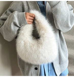 Close-up of white plush faux fox fur handbag with fluffy dumpling shape and soft texture