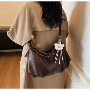 Detailansicht der großen dunkelbraunen Ledertasche mit Faltenstruktur und Bärenanhänger