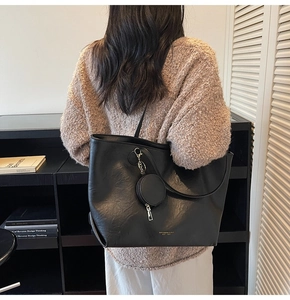 Detailed view of black leather tote bag with a small round coin purse and gold lettering