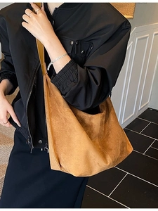 Caramel brown large faux suede tote bag crossbody worn by model in a modern room