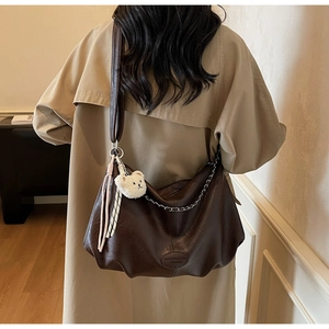 Detailansicht der großen dunkelbraunen Hobo-Tasche mit Silberkette und Bärenanhänger-Deko