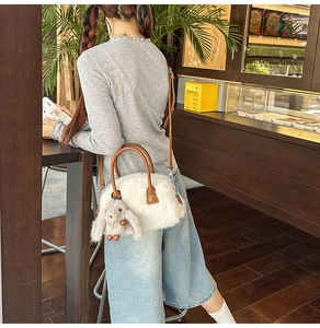 Detail of white faux fur handbag with brown leather handles and cute rabbit charm