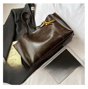 Close-up of coffee brown tote bag with vertical stitching and wooden bead tassel detail