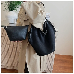 Detail of black suede tote bag with matching leather pouch worn with a beige trench coat