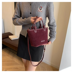Detail showing the burgundy suede texture and brand logo of the women's bucket bag