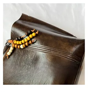 Macro detail of dark brown oil wax leather tote bag with retro wooden beads and stitching